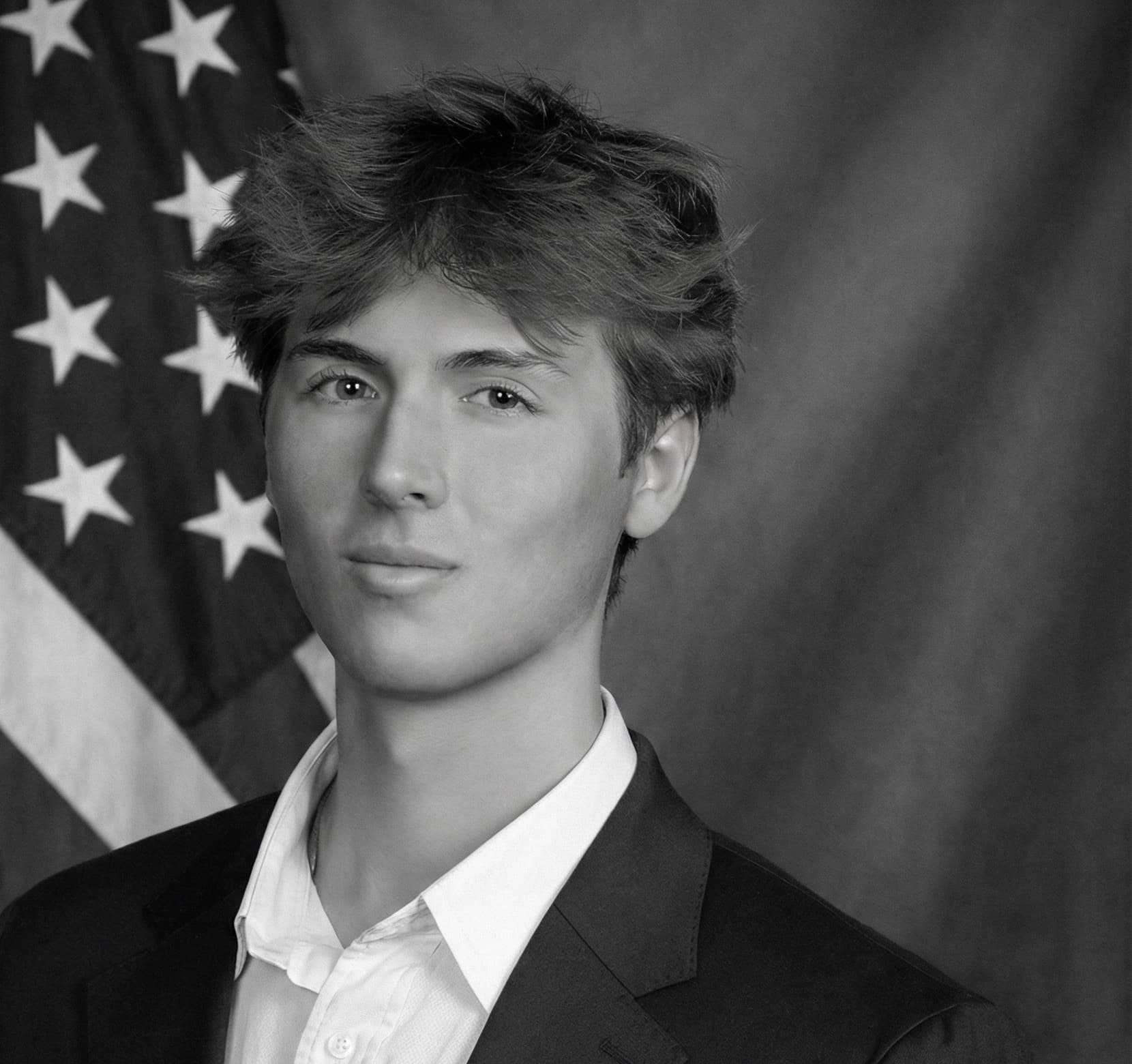 Black-and-white studio portrait of Caden Tacoronte in a dark suit and white shirt.