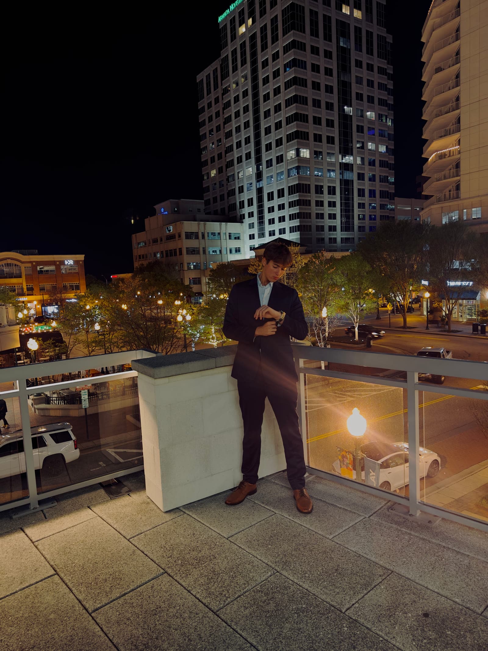 Caden Tacoronte checking his watch on a downtown terrace at night.